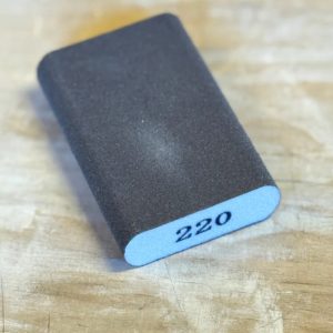 Esponja abrasiva redondeada para madera grano fino 220 Magic Paint sobre superficie de madera